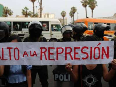 Protesters hold a sign saying “alto a la represión” (stop the repression) in front of a line of riot police during the 12-hour raid on the Peasant Confederation of Peru in Lima on December 17, 2022.