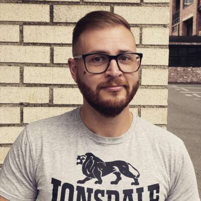 a photo of shane burley a white man with glasses and brown hair and cleanly shaven beard.