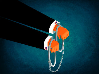 Tiny orange hands poke out of an oversized suit and are ineffectively bound by handcuffs too large to actually restrain them