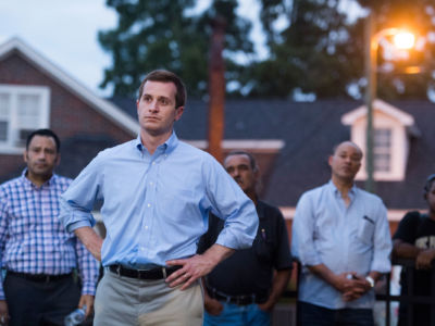 Dan McCready stands with his hands on his hips in front of people's homes