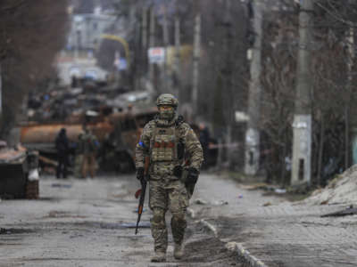 A soldier in uniform stands alone in the middle of a street