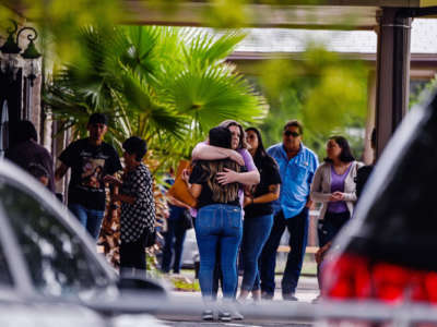 Two people embrace eachother outside of a funeral home