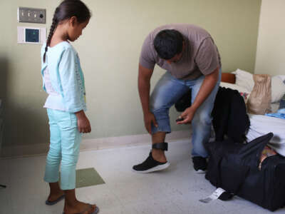 Selena watches as her father Luis (only first name was provided) works on changing the battery in his ankle monitor as they are cared for in an Annunciation House facility after they were reunited on July 26, 2018, in El Paso, Texas.