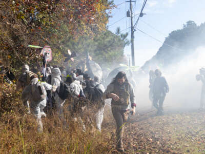 Journalist Matt Scott with the Atlanta Community Press Collective moves away from a cloud of tear gas thrown by Georgia law enforcement in Atlanta, Georgia on Monday, Nov. 13, 2023. ‘Stop Cop City’ activists gathered from across the United States to attend the ‘Block Cop City’ march to the construction site for the Atlanta Public Safety Training Center.