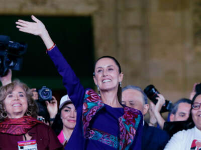 Claudia Sheinbaum waves to supporters from a podium