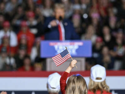 A child holds a small American flag as Republican presidential candidate and former President Donald Trump speaks during a campaign rally at the Ryder Center for Health and Physical Education at Saginaw Valley State University in Saginaw, Michigan, on October 3, 2024.