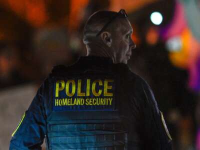 A Department of Homeland Security agent stands guard as protesters demonstrate against recent raids conducted by the US Immigration and Customs Enforcement (ICE) outside the DHS office in Charlotte, North Carolina, on November 16, 2025.