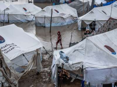 A boy walks through a waterlogged alley at a makeshift camp sheltering displaced Palestinians after heavy rains in the Zeitoun neighborhood of Gaza City on December 11, 2025.