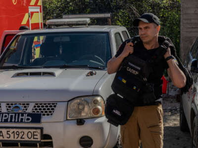 Yaakov puts on his flak jacket as the team prepares to head out to the field on the outskirts of Kyiv’s suburb of Irpin in April 2025.