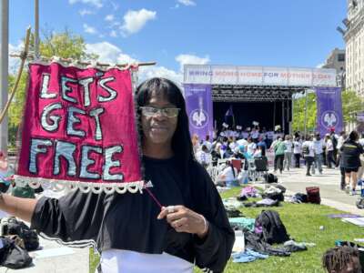 Avis Lee holds a banner for Let's Get Free, the Women and Trans Prisoner Defense Committee which helped with her fight for freedom and with which she now organizes to free others.