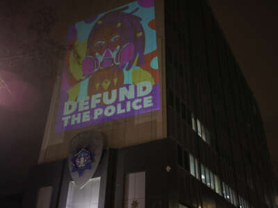 A protester projects ''Defund The Police'' on the wall of the Oakland Police Department as people gather at the Frank H. Ogawa Plaza following the police-perpetrated killing of Tyre Nichols by Memphis police, in Oakland, California, on January 29, 2023.