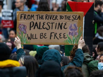 A pro-Palestinian activist holds up a sign reading 'From The River To The Sea Palestine Will Be Free' during a sit-down protest inside Charing Cross railway station to call for an immediate ceasefire in Gaza on November 4, 2023, in London, United Kingdom.