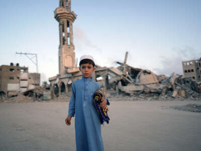 A Palestinian boy carrying his prayer mat poses for a picture before joining the morning Eid al-Adha prayer in Khan Younis in the southern Gaza Strip, on June 16, 2024.