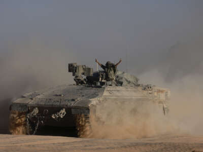 An Israeli soldier gestures from an armored personnel carrier on the border with the Gaza Strip on July 17, 2024.