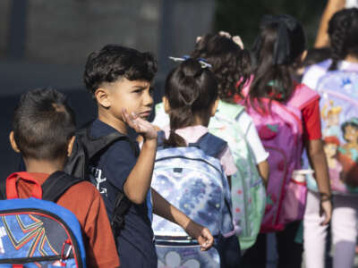 A student waves goodbye as he heads to his classroom on the first day of school at Price Elementary School in Anaheim, California, on August 8, 2024.