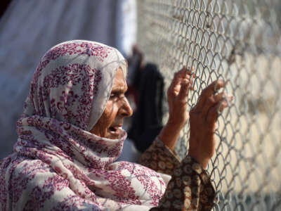A displaced Palestinian woman looks through a fence in a tent camp in Khan Younis, southern Gaza Strip, on November 9, 2024.