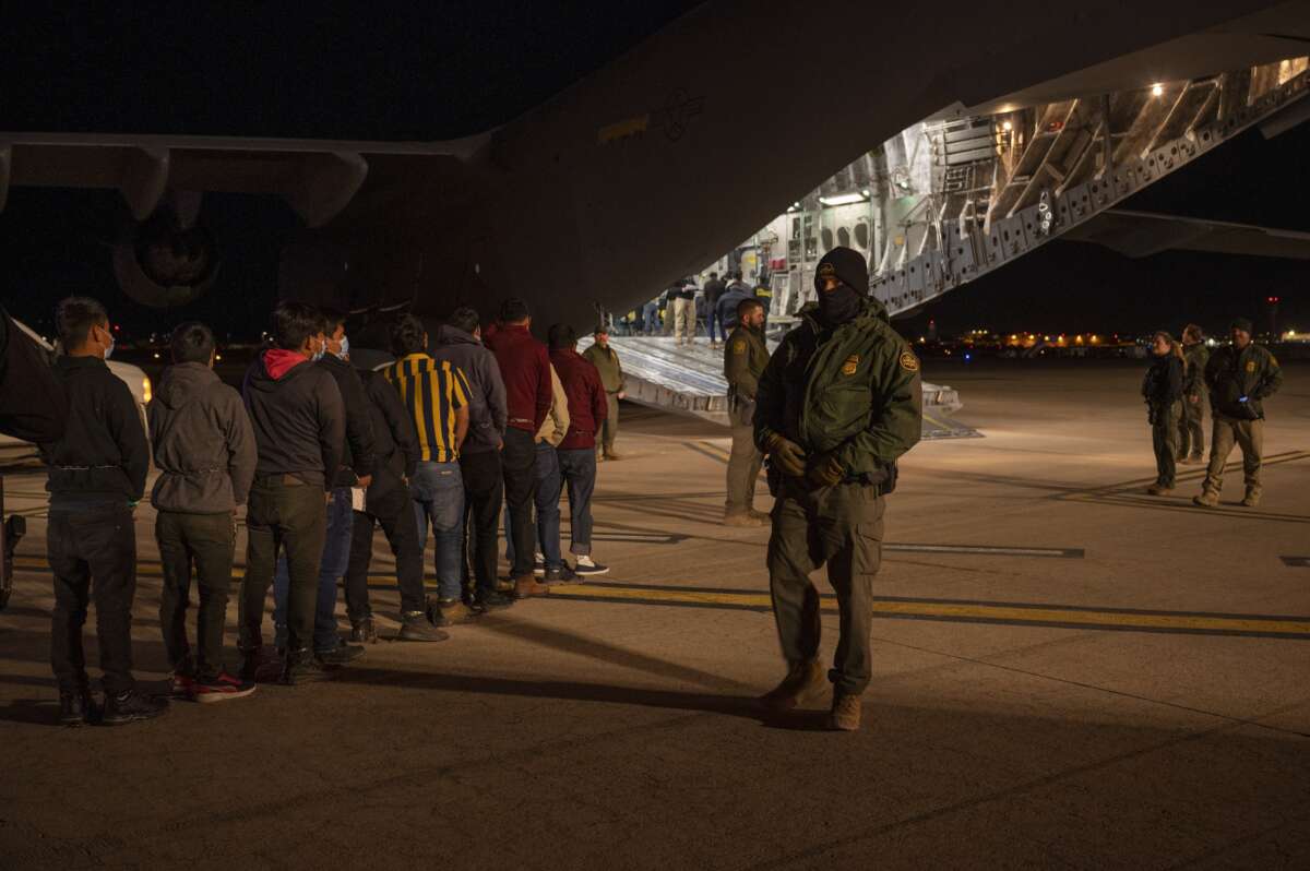 U.S. Customs and Border Protection Agents watch immigrants board a deportation flight at the Tucson International Airport, in Tucson, Arizona, on January 23, 2025.