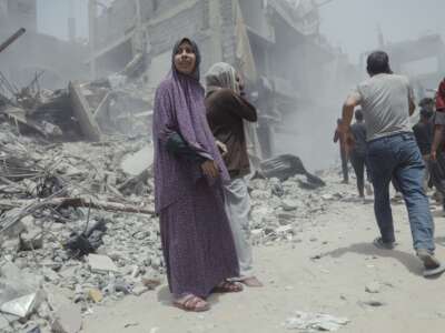 Palestinian civilians walk past collapsed structures and debris in the aftermath of an Israeli airstrike in Gaza, on May 17, 2025.