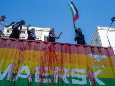 Protesters on top of a Maersk vehicle chant anti-genocide slogans while flying a Palestine flag on June 14, 2025, in Warsaw, Poland.