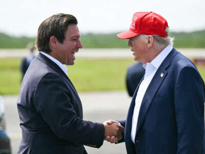(L/R) Florida Governor Ron DeSantis shakes hands with U.S. President Donald Trump upon Trump's arrival at Dade-Collier Training and Transition Airport in Ochopee, Florida, on July 1, 2025.