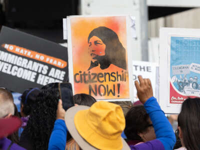 Protesters are holding up signs that read "citizenship now."