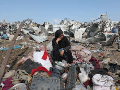 A displaced Palestinian woman sits with her belongings after an Israeli strike on at a camp for internally displaced people in Deir el-Balah in the central Gaza Strip, on August 21, 2025.