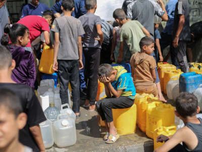 Palestinian children sit on their containers as they queue for water at a charity distribution point in the Nuseirat refugee camp in the Israel-besieged Gaza Strip on September 4, 2025.