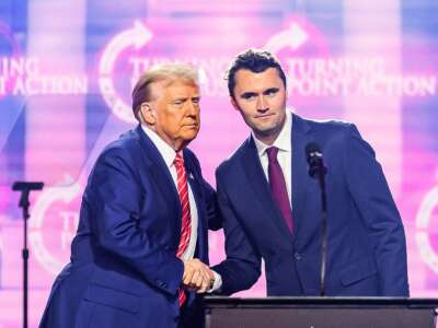 Right-wing activist Charlie Kirk speaks on stage with Donald Trump at America Fest 2024 in Phoenix, Arizona, on December 22, 2024.