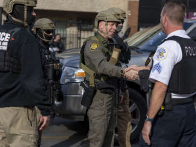 Border Patrol Cmdr Gregory Bovino shakes hands with Chicago police Sgt. Glenn Polanek while the Border Patrol's convoy of vehicles stopped on November 6, 2025, next to Marquette Park on Chicago's South Side.