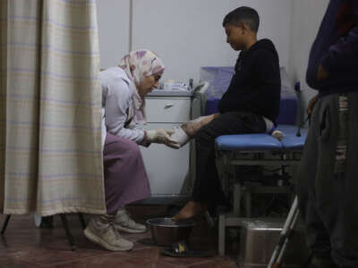 A medical personnel assists a young displaced Palestinian amputee at the Sheikh Hamad Hospital for Rehabilitation and Prosthetics in Gaza City, on November 16, 2025.