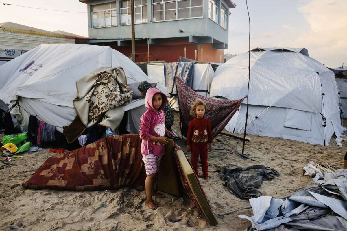 Palestinian children move mattresses to protect them from the rain at a makeshift camp housing displaced Palestinians in Deir al-Balah, in the central Gaza Strip, on November 25, 2025. With many displaced living in tent camps, the coming winter is raising serious concerns.