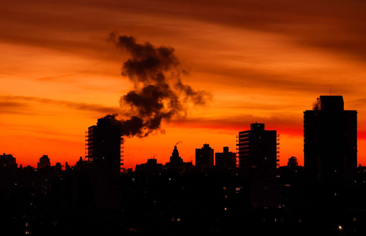 An emission comes out of a smoke stack as the sun rises in New York City on December 28, 2025, as seen from Jersey City, New Jersey.