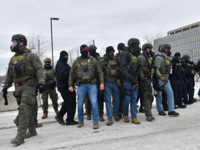 Federal agents stand guard while facing anti-ICE protesters outside the Bishop Whipple Federal Building in Minneapolis, Minnesota, on January 15, 2026.