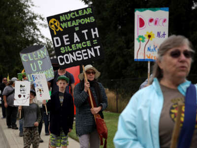 Protester holds sign saying "Nuclear weapons = death. Silence = consent."